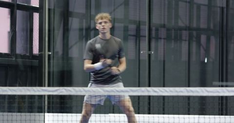 Young male tennis player practicing on indoor court