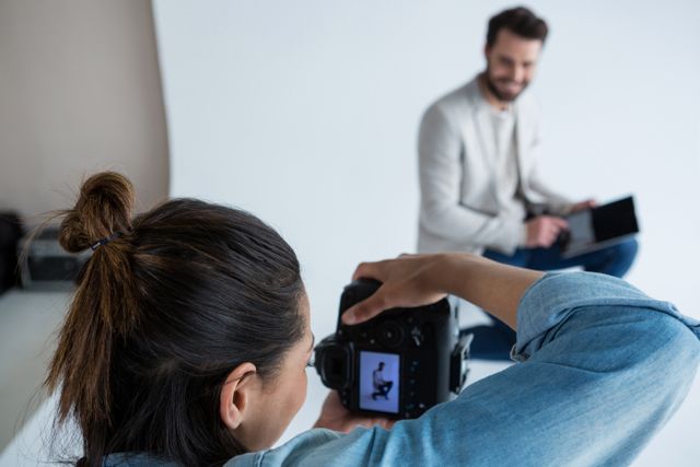 Male model posing for a professional photoshoot in a studio. Photographer capturing images with a digital camera. Ideal for use in articles about fashion photography, modeling, creative industries, and professional photo sessions.