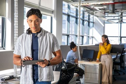 Young asian man using tablet in modern open-plan office with collaborative diverse team