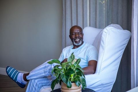 Elderly man relaxing in chair with potted plant at home