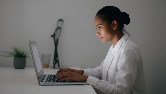 Professional Woman Focusing on Laptop at Modern Office Desk