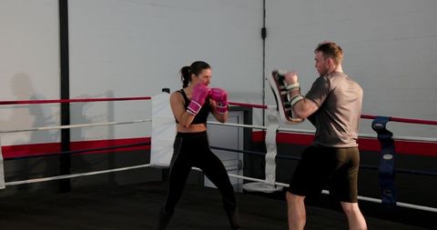 Female Boxer Sparring with Coach During Intense Padwork Training and Fitness Workout in Boxing Ring