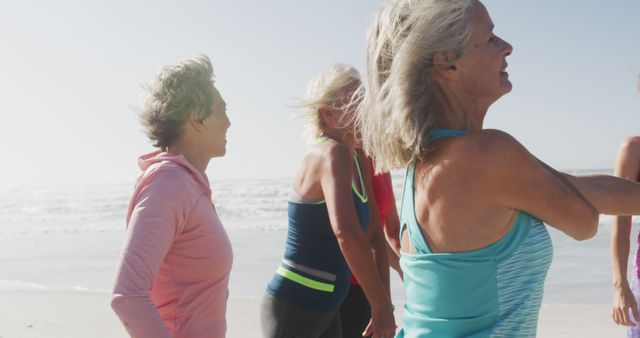 Senior women engaging in a group exercise session on the beach, smiling and enjoying the sunny day. Ideal for use in promoting active lifestyles for older adults, beach fitness programs, retirement wellness, fitness programs for women, and outdoor recreational activities.