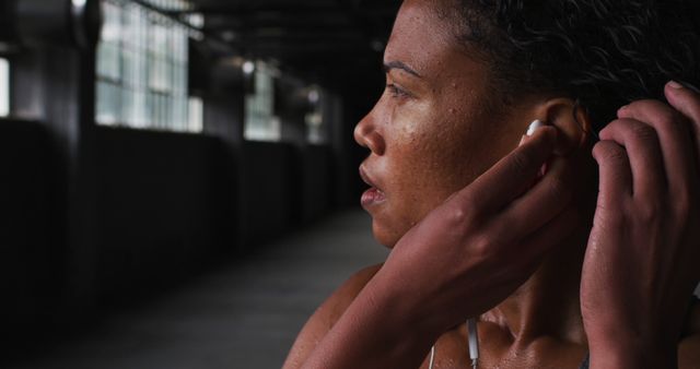 Focused Athlete Adjusting Earbuds During Intense Workout in Urban Environment - Download Free Stock Images Pikwizard.com