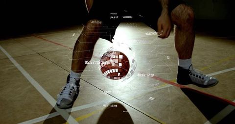 Low-angle basketball player dribbling with futuristic hud overlay on indoor court