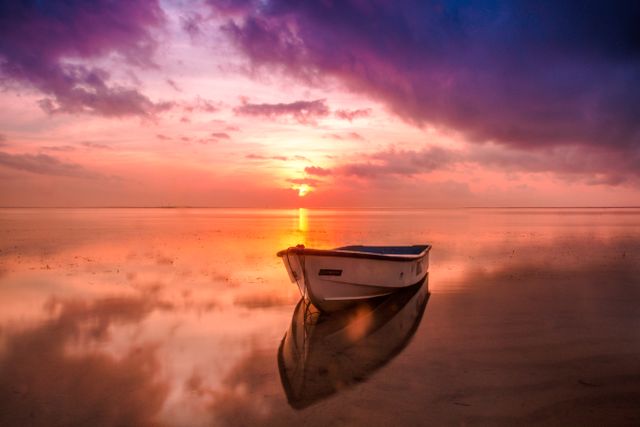 Serene Sunrise with Boat on Calm Beach - Download Free Stock Photos Pikwizard.com