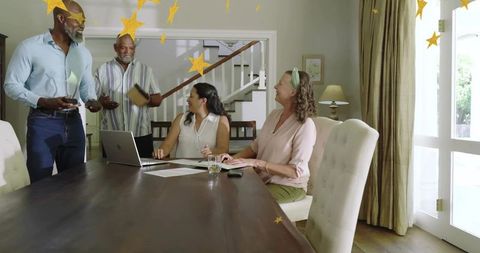 Multigenerational adults gathering around dining table discussing finances with laptop