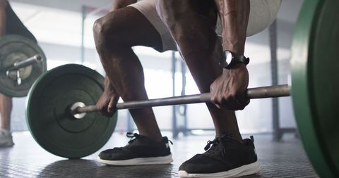 Focused Man Performing Deadlifts with Barbell in Gym Setting