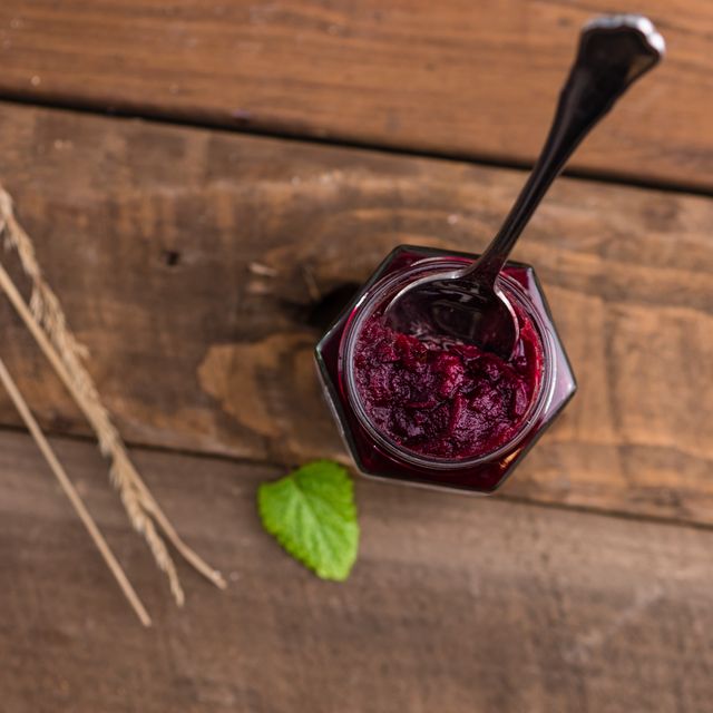 Homemade beetroot jam in glass jar, seen from top view, on rustic wooden table. Image highlights a traditional and artisanal food item, perfect for use in cooking blogs, food-related websites, and advertising natural or organic products.