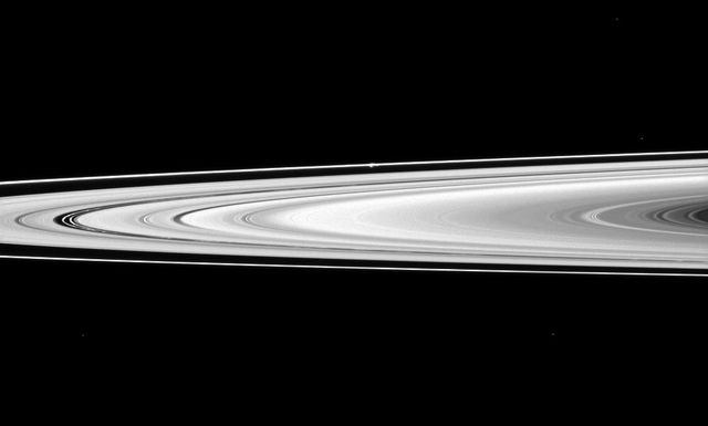 NASA Cassini spacecraft looks across Saturn rings and finds the moon Prometheus, a shepherd of the thin F ring. Prometheus looks like a small white bulge near the F ring -- the outermost ring seen here -- above the center of the image.