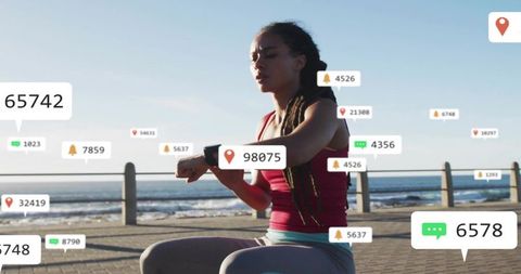 Female runner checking smartwatch on seaside promenade with fitness and social notifications