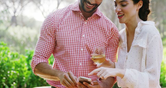 Romantic couple using mobile phone while having glass of drink
