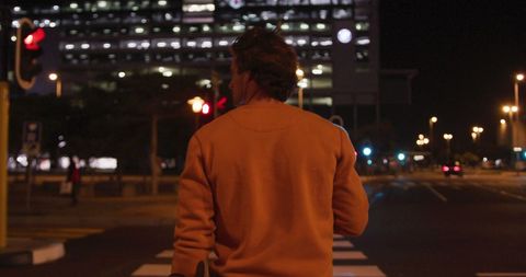 Man Enjoying Nighttime City Walks with Smartphone and Earphones