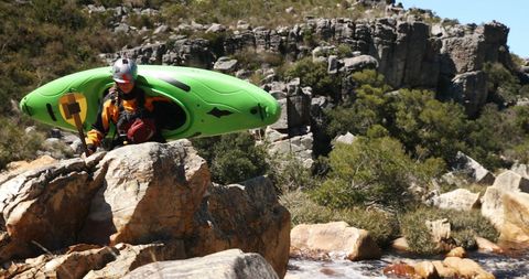 Kayaker preparing for river descent on rugged terrain