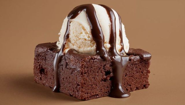 Fudgy chocolate brownie squares with vanilla ice cream scoop dripping dark chocolate sauce