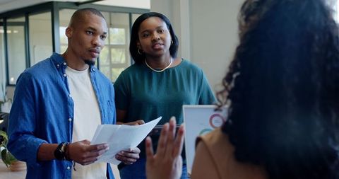 African american couple reviewing financial charts with advisor at bright office reception