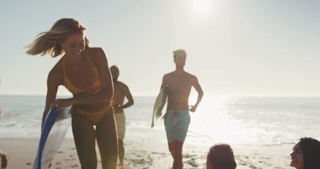 Diverse and smiling men and woman returning from surfing at sunset. Summer, free time, friendship, vacation.