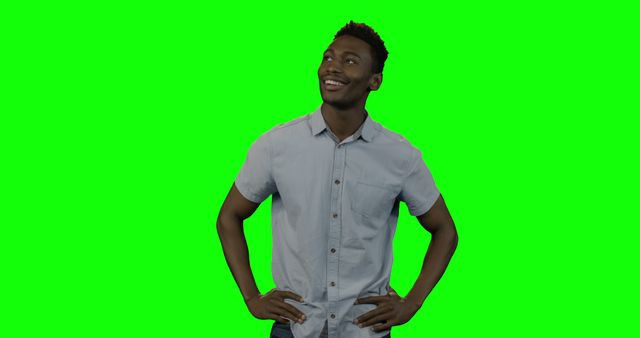 Capturing a confident African American man standing and smiling against a bright green screen. Suitable for various marketing materials, advertisements, and any creative project requiring isolated background removal. Perfect for promoting positivity, casual fashion, and youth-related content.