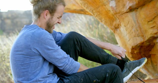 Man tying laces on hiking shoes in rocky outdoor setting - Download Free Stock Images Pikwizard.com