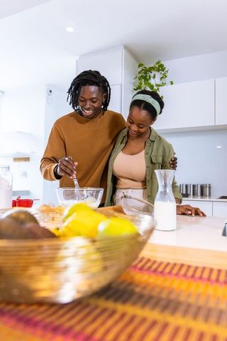 African american couple cooking together in bright modern kitchen stirring batter