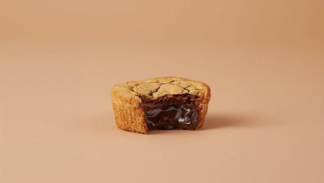 Cookie cup releasing molten chocolate ganache on beige minimal tabletop