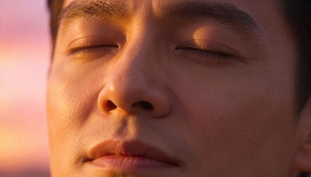 Closeup portrait asian man soaking golden-hour light, showing skin glow and calm expression