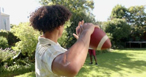 Young Adults Playing Football in Sunny Garden