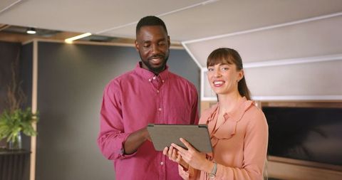 Diverse business colleagues collaborating with tablet in modern office