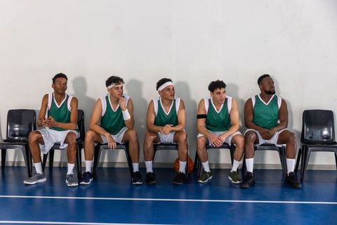 Basketball Teammates Sitting on Bench in Sporting Arena