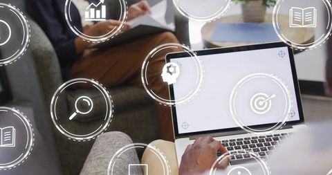 Typing on Laptop in Casual Office Lounge with Superimposed Digital Teamwork Icons