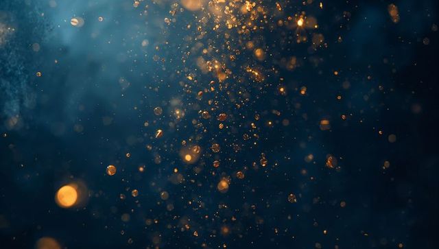 Golden bokeh particles floating over deep teal navy background with luminous droplets