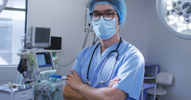 Confident surgeon standing in operating room with medical equipment and monitors in background. Ideal for use in healthcare and medical websites, blogs about surgery or hospital operations, promotional material for hospitals, medical recruitment advertisements, health insurance campaigns, and educational content for medical students.