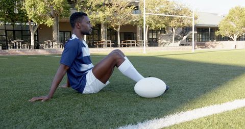Rugby Player Resting On Field With Ball