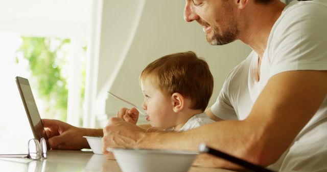 Father and son using digital tablet during breakfast - Download Free Stock Images Pikwizard.com