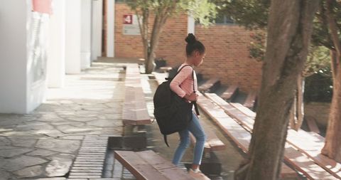 Child carrying backpack in school courtyard