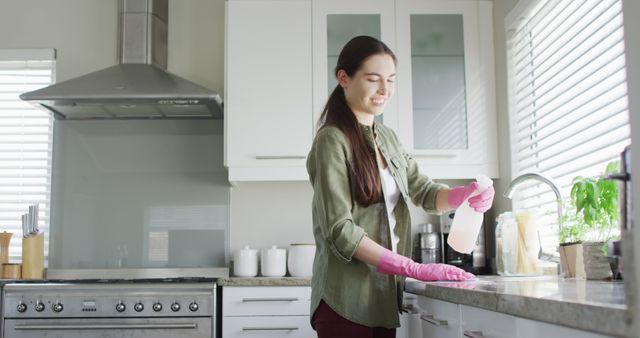 Caucasian woman wearing rubber gloves and cleaning table in kitchen. Lifestyle and domestic life concept.