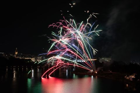 Festive Fireworks Illuminating Riverside Cityscape at Night