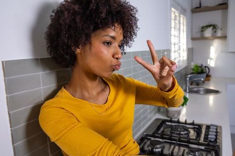 Casual woman posing with peace sign in modern kitchen