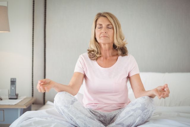 Senior sitting on bed and practicing yoga in bed room