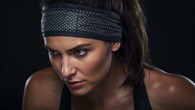Sweaty athlete focusing during intense workout, polka-dot headband, dramatic lighting