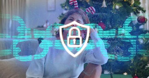 Senior woman wearing candy-cane headband showing cybersecurity shield for holiday online safety