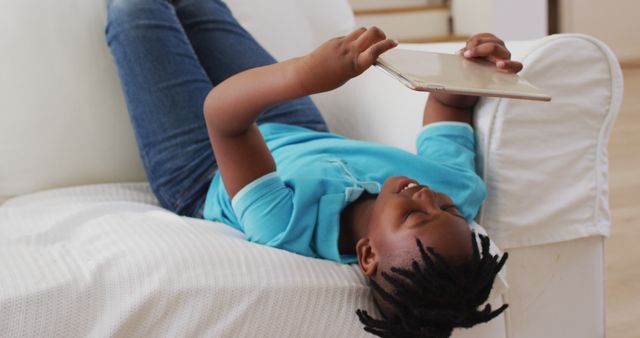 Happy Young Boy Reading on Tablet While Lying on Couch at Home - Download Free Stock Images Pikwizard.com