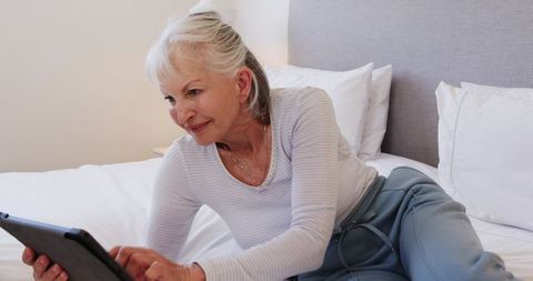 Senior Woman Relaxing on Bed with Tablet Device
