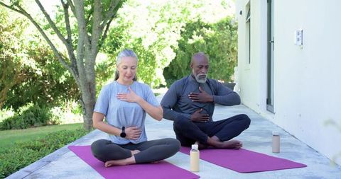 Mature african american couple practicing paired mindfulness and breathwork on patio yoga mats