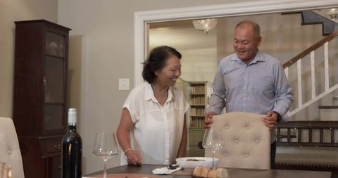 Laughing couple sharing intimate dinner moment in cozy home dining room