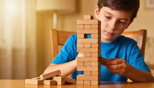 Boy building tower with toy bricks practicing concentration and fine motor skills