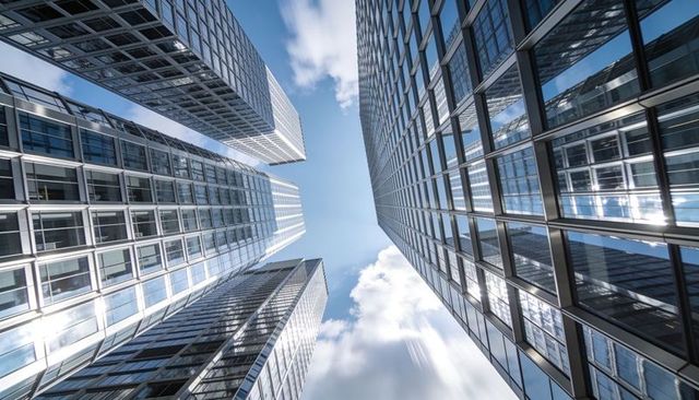 Converging glass skyscrapers reflecting blue sky symmetry vertical urban architecture