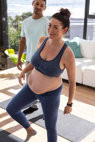 Pregnant Woman Stretching with Supportive Partner in Scenic Home
