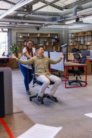 Playful Coworkers Rolling Chair in Modern Office Environment
