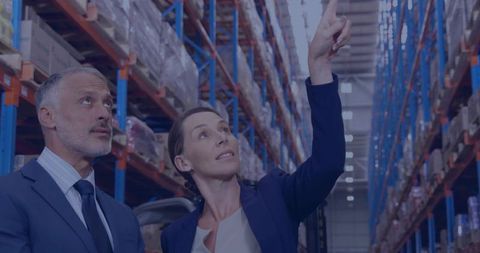 Woman manager pointing while man inspecting pallet racks with animated stock tags